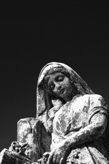 A statue of the Virgin Mary looking sad in a black and white.