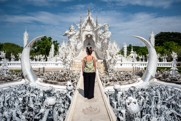 Mujer entrando al templo wat rong khun, en la ciudad de Chiang Rai