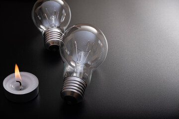 Electric lamp and candle on a dark background.  Incandescent bulb and candle. Power cut or power...