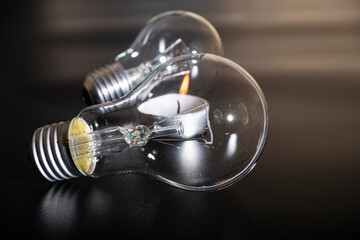 Electric lamp and candle on a dark background.  Incandescent bulb and candle. Power cut or power...