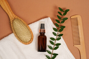 Spa body care products wooden hair brushes and oil in glass bottle on white towel