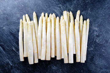 Roher weißer Spargel mit einer Reihe als close-up mit Textfreiraum oben auf grauem Hintergrund