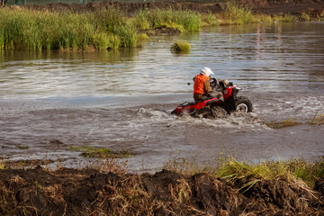 athlete on a quad bike rides in the swamp