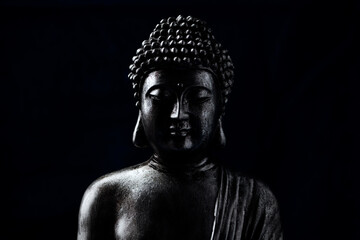 Meditating Buddha Statue on dark background. Soft focus. Close up. Copy space.	