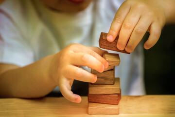 close-up of a child's hand building a pyramid of wooden cubes