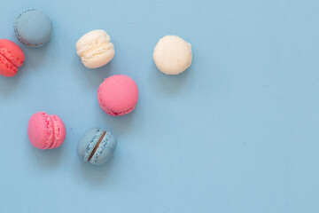 Obraz na płótnie Canvas Colorful macaroon cookies arranged on blue background, top view, with blank space 