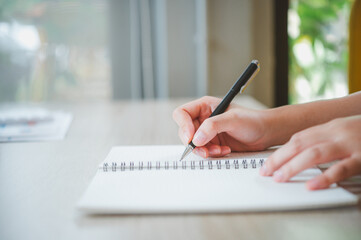 Closeup of woman's hand writing on book