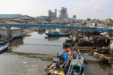 Obraz premium portrait of traditional fishing boats in fishing village beside industrial factory