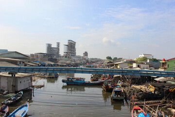 portrait of traditional fishing boats in fishing village beside industrial factory