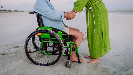 Obraz premium Senior man on wheelchair enjoying together time with his wife at sea, low section.