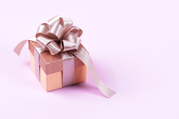Lilac festive gift box with a satin ribbon bow on a lilac background. Happy Valentine's Day, Mother's Day and birthday greeting card.