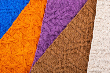Knitted blue, lilac, brown, orange and beige background. Large knitted fabric with a pattern. Close-up of a knitted blanket.