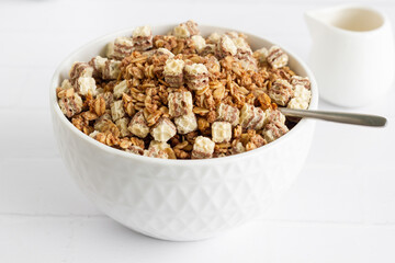 A bowl of breakfast cereal with milk on white table