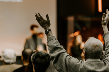 Elder man rise his hand while he is praise God at church service