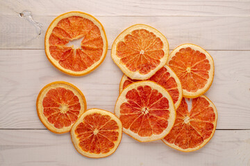 Several dry slices of grapefruit on a wooden table, macro, top view.