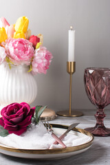 a white vase with flowers and a glass of wine on the table. Romantic table setting