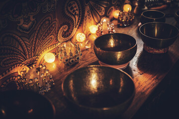 A closeup of perfumes bottles in candlelight and tibetan bowls.