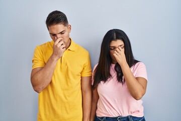 Young couple standing over isolated background tired rubbing nose and eyes feeling fatigue and headache. stress and frustration concept.