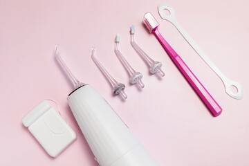 Oral hygiene set. Oral teeth irrigator with nozzle pack, toothbrush, dental floss, tongue scraper. Top view, pink background Dental care, treatments, daily routine. Horizontal , closeup