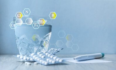 a glass of water, tablets, a pen.icons with microelement symbols. Supplements. health concept. Copy space