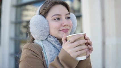 Young blonde woman smiling confident drinking coffee at street