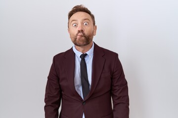 Middle age business man with beard wearing suit and tie making fish face with lips, crazy and comical gesture. funny expression.