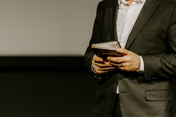 Pastor with a Bible in his hand during a sermon. The preacher delivers a speech - 570934156