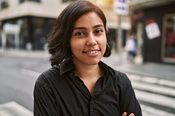 Young latin woman smiling confident standing with arms crossed gesture at street