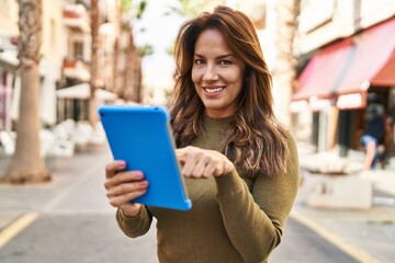Young latin woman smiling confident using touchpad at street