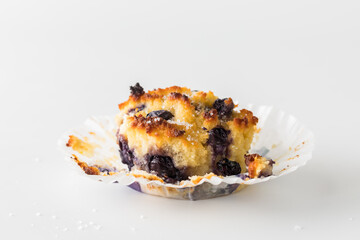 Close up of a blueberry muffin with the paper liner peeled back.
