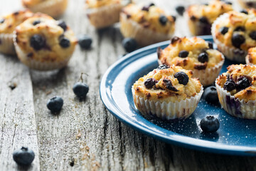 Several homemade low carb blueberry muffins on rustic wood and lit from behind.