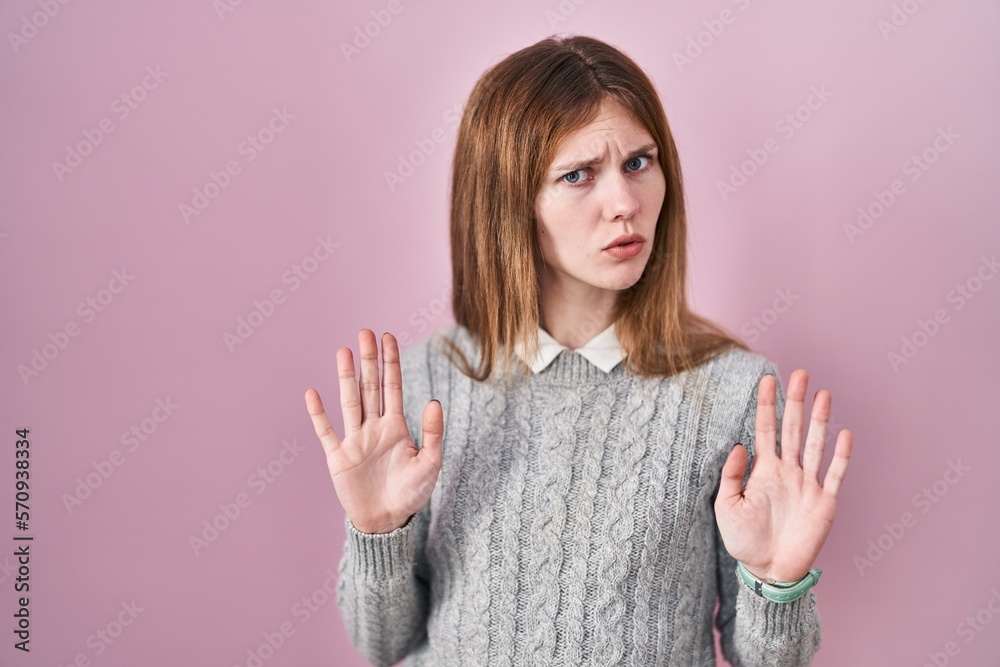 Poster beautiful woman standing over pink background moving away hands palms showing refusal and denial wit