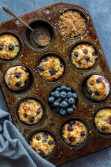 Flatlay view of a rustic muffin tin filled with homemade blueberry muffins