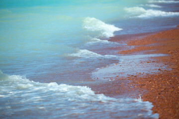 Waves on the sandy beach. Water background, blue sea water. Beautiful texture of sun glare on the...