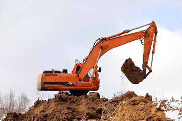 Crawler excavator scoops the earth with a bucket. Earthmoving works, digging on a construction site