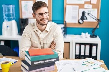 Young caucasian man business worker smiling confident sitting with arms crossed gesture at office