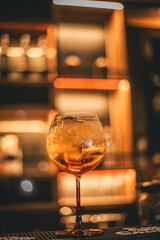 Ramazzotti Spritz color naranja, en la barra de un bar nocturno decorado con luces cálidas desenfocadas