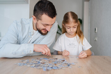 Fototapeta premium father and daughter playing with puzzles at home. Focus on man.