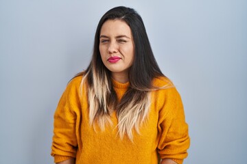 Young hispanic woman standing over isolated background winking looking at the camera with sexy...