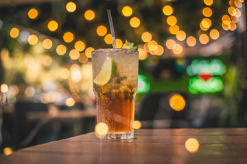 Colorido y refrescante Mojito cubano en la mesa de un bar, decorado con preciosas luces cálidas desenfocadas en el fondo