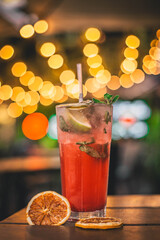 Colorido y refrescante Mojito cubano en la mesa de un bar, decorado con preciosas luces cálidas desenfocadas en el fondo