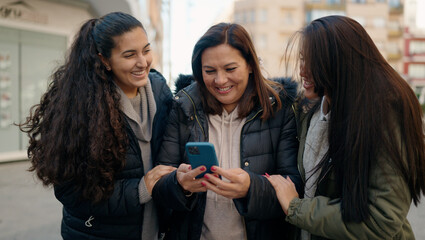 Mother and daugthers using smartphone standing together at street