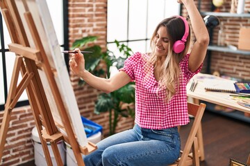 Young woman artist listening to music drawing at art studio