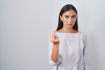 Young hispanic woman standing over white background showing middle finger, impolite and rude fuck off expression
