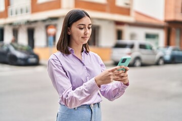 Young hispanic woman smiling confident using smartphone at street