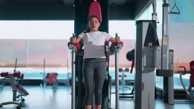 Crossfit training. asian sport female doing abdominal exercise with rising up her leg with machine. Functional training workout, personal circuit training, fitness class