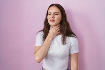Fototapeta premium Young hispanic girl standing over pink background touching painful neck, sore throat for flu, clod and infection
