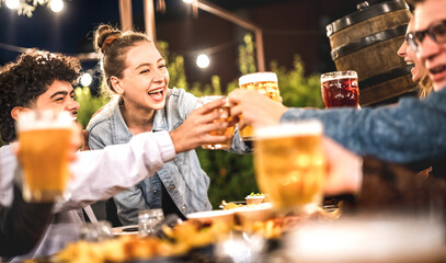 Happy friends toasting beer at brewery restaurant patio - Life style and beverage concept with young people having fun together out side at patio garden by night - 570946195