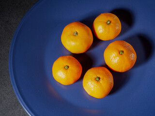 one orange mandarin on blue plate