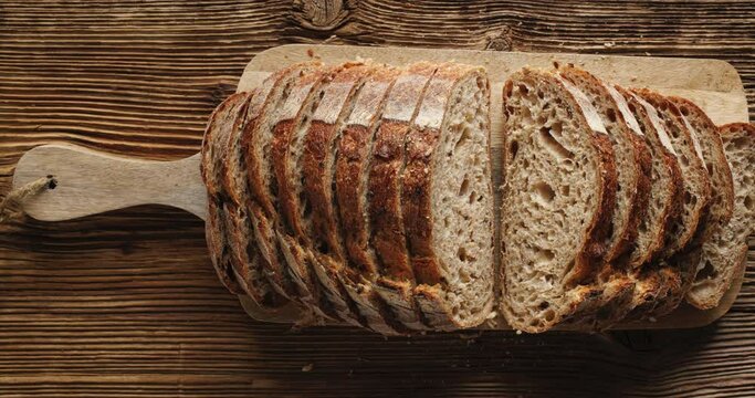 Slicing sourdough bread on a wooden board, close up view. Traditional artisan bread cut into slices